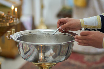 Photo of the process of consecration of water by the church priest during the ceremony of baptism of a child