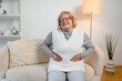 © Serhii - Senior woman sitting on her bed has stomach ache