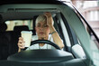 © Davor - Senior female medical professional holding head in stress during coffee break in car