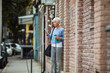 © Davor - Senior woman checking phone while walking with gym gear and water bottle