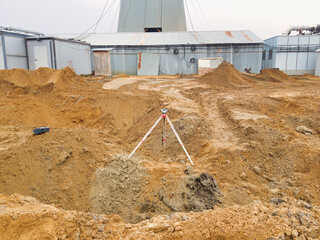 construction site with excavation and surveying equipment under overcast skies in an industrial area