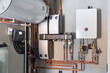 © GarkushaArt - Heating system equipment in a boiler room of modern private house. Wall installation of electric boiler device, valves, pumps, cooper tubing, water heater, automatic controller in a single family home