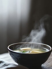 Poster - Steaming bowl of miso soup with tofu and seaweed illuminated by natural light