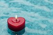© Arfa_Media - Red heart-shaped candle floating on turquoise water surface