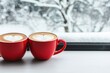 © Arfa_Media - Two red coffee cups with heart latte art by a window in winter