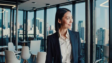 Confident businesswoman holding tablet computer looking out large office window at inspiring cityscape view contemplating future business vision