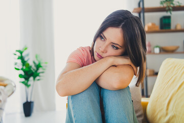 Wall Mural - Pensive woman sitting indoors in cozy apartment, reflecting during daylight