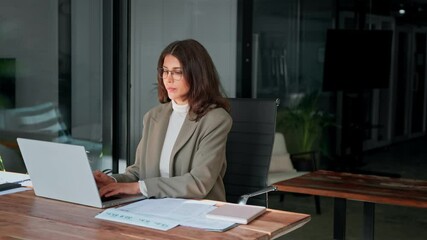 Young professional it specialist latin hispanic business lady working on laptop pc sitting at desk in modern office space. 30s middle eastern indian woman using computer technology app for work online