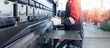 © Parilov - Caucasian male adult operating industrial press brake machine in factory setting