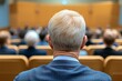 © top images - Man with a bald head sits in a crowded auditorium