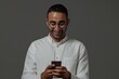 © Harsha - Happy mid adult man texting on smartphone on grey background.