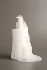 Canvas Print - Bottle of cosmetic product with foam on grey background