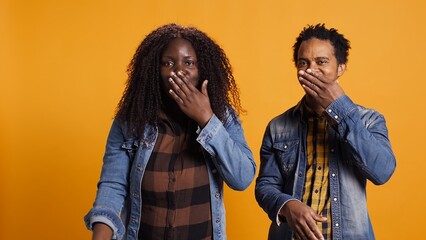 Wall Mural - Cute romantic married couple sending air kisses and posing together, smiling and feeling grateful for each other. African american man and woman acting flirty in studio. Camera B.