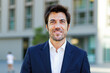 © Minerva Studio - Portrait of a smiling businessman standing in front of an office building