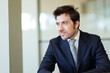 © Minerva Studio - Pensive businessman looking away while sitting at desk in office