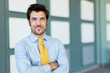 © Minerva Studio - Confident businessman with arms crossed smiling in modern office