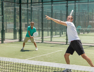 Wall Mural - Four men practice playing padel on an outdoor tennis court