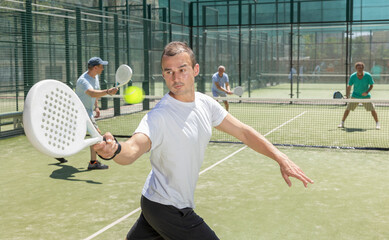 Wall Mural - Sportive man engaged in padel in open-air court of tennis club