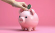 © RooftopStudioBangkok - Hand placing coin in pink piggy bank, symbolizing savings and financial growth. vibrant background enhances cheerful theme of saving money