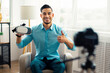 © Prostock-studio - Trendy Arab influencer filming brand advertising promo, presenting VR headset at camera from home. Happy guy vlogger recording video about innovative device for technology blog. Tech product review