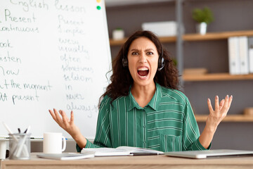 Aufkleber - Professional Job Burnout. Portrait of exhausted angry lady tutor in headphones screaming out loud, irritated lady gesturing and looking at camera teaching English language online, sitting at desk