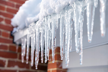 Poster - Icicles hanging from a snowy roof in winter.