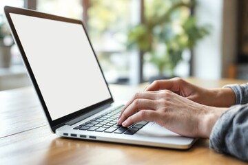 Poster - Blank laptop screen mockup on wooden desk with hands typing in a bright room.