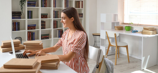 Wall Mural - Happy female student with laptop and books studying in library