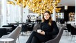 © mashimara - Elegant Woman in Modern Cafe: A sophisticated young woman with long brown hair sits gracefully in a modern cafe, enjoying a cup of coffee. The ambiance is chic and upscale.