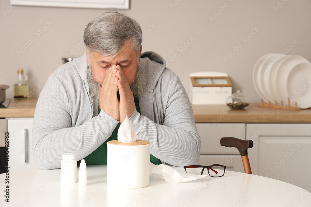 Portrait of sad senior man with tissues sitting at table in kitchen