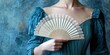 © MdMoinul - Woman in a blue regency dress holding an elegant white lace fan
