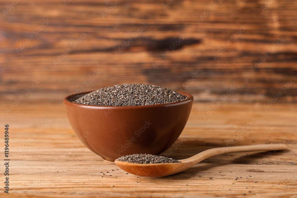 Bowl and spoon with chia seeds on wooden background