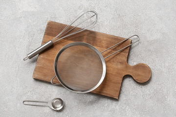 Wall Mural - Wooden board with metal sieve, whisk and scoop on grunge background