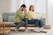 © Pixel-Shot - Young man apologizing to his wife on sofa at home