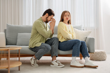 Wall Mural - Young man apologizing to his wife on sofa at home