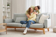 © Pixel-Shot - Apologizing young man hugging his wife on sofa at home
