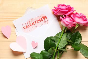  Composition with rose flowers, paper hearts and envelope with greeting card on wooden background. Valentine's Day celebration