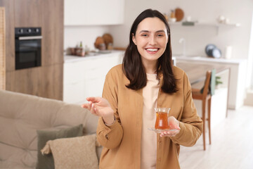 Poster - Young woman with Turkish tea in kitchen