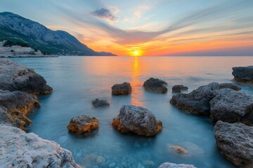 Wall Mural - Golden sunset illuminating calm waters and rocks on croatian coast