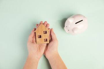 Wall Mural - Savings concept. Woman holding piggy bank and house model