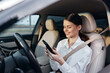 © SHOTPRIME STUDIO - Woman in car using phone, smiling and looking at screen while interacting with her device