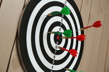 Dart board with colorful arrows on wooden background, closeup