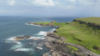 Wall Mural - Drone view of a rocky shore with moss-covered cliff by the sea under clear sky on a sunny day