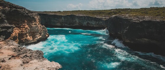 Aufkleber - Waves crash against rocky shore under clear skies by the vast ocean in a tropical paradise