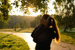 © deine_liebe - Young woman listening to music and doing breathing exercises in the open air. Red-haired girl meditates while standing against the background of nature.