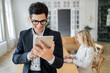 © muse studio - Man smiling while using tablet in modern office with woman working nearby