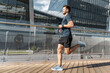 © muse studio - Man jogging on a wooden deck near modern buildings during bright daylight