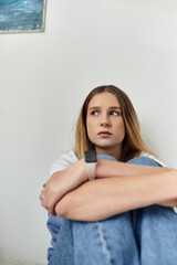 Wall Mural - A pretty teenage girl sits thoughtfully in her room, embracing youth and personal style.