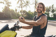 © BullRun - Young male biker sitting on motorcycle among beach