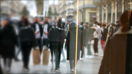 Crowd in street walking and shopping on glass reflection, blurred city life